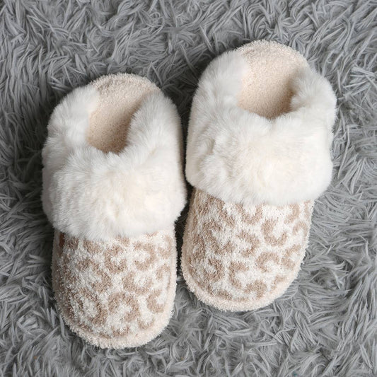 Pair of white fuzzy slippers on a gray textured surface