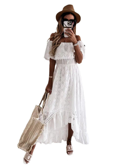 Woman wearing a white lace dress with a brown hat and holding a beige bag on a white background