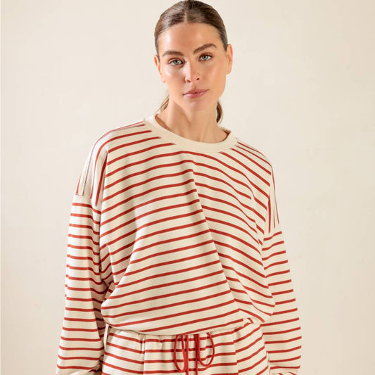 Woman wearing a red and white striped pajama set against a beige background