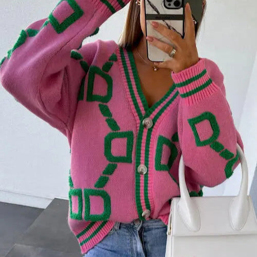 Person wearing a pink cardigan with green patterns, holding a white handbag.