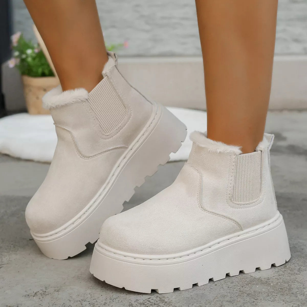 White platform boots with fur lining worn by a person on a neutral background