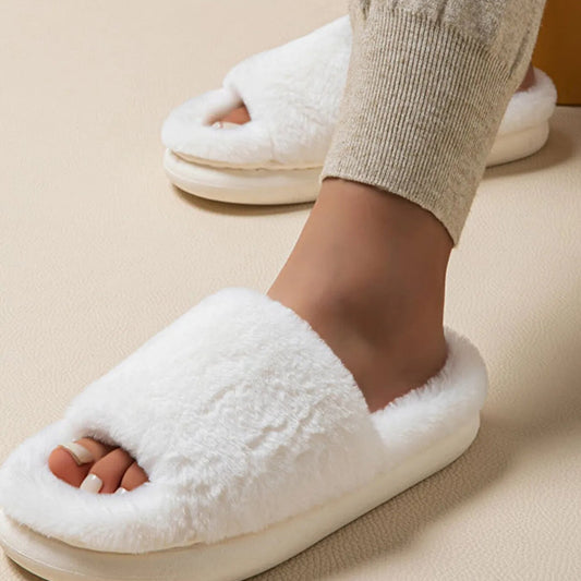 White fluffy slippers worn by a person on a beige background