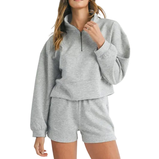 Person wearing a gray hoodie and shorts set on a light gray background