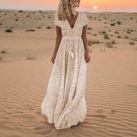 Woman in a white polka dot dress standing in a desert landscape with a sunset.