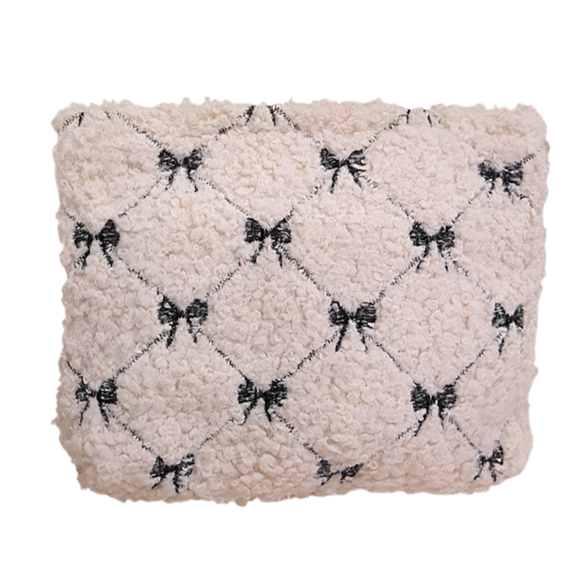 Textured beige pillow with black bow pattern on a white background