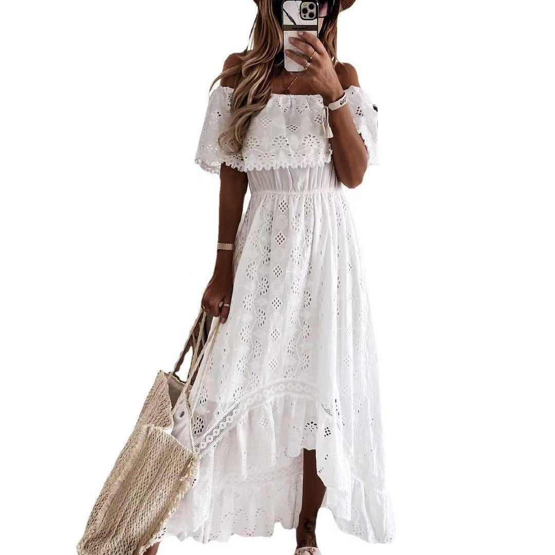 Woman wearing a white lace dress with a brown hat and holding a beige bag on a white background