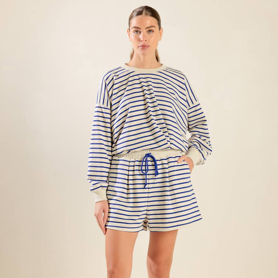 Woman wearing a striped outfit with shorts on a beige background