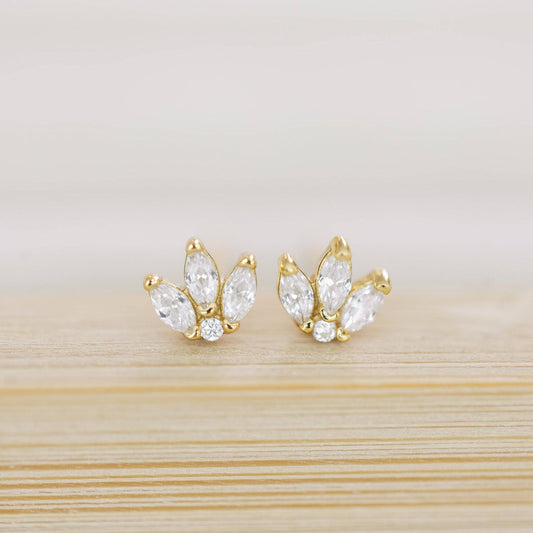 Gold earrings with clear stones on a light wooden surface