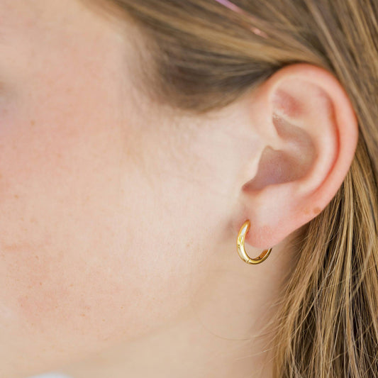 Gold hoop earring worn by a person with blonde hair.