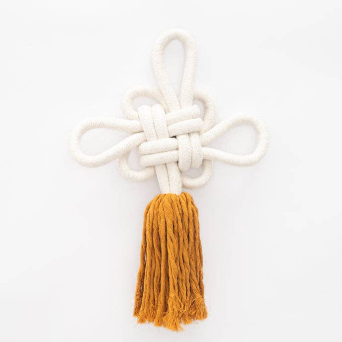 White knotted rope with a mustard yellow tassel on a white background