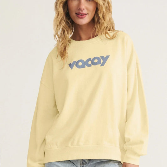 Woman wearing a light yellow sweatshirt with 'Voyag' text on a plain background