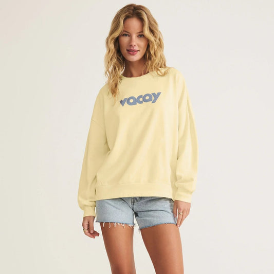 Woman wearing a yellow sweatshirt with 'Voyay' logo on a plain background